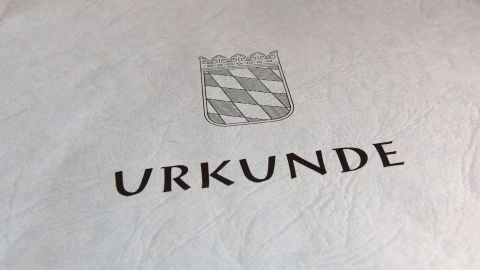 Beim Kauf von Wohnungen mit Denkmalschutz Steuern sparen. Eine Urkunde mit einer Wappenzeichnung, die den Erwerb einer denkmalgeschützten Wohnung dokumentiert.