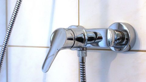 Ein glänzender Wasserhahn wird mit Teflonband abgedichtet, um Gewindeverbindungen gegen Leckagen zu sichern.