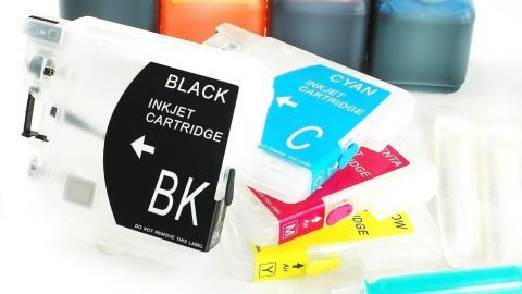 Druckerpatronen liegen verstreut auf einem Tisch, einige sind voll, andere zeigen trockene Tinte.