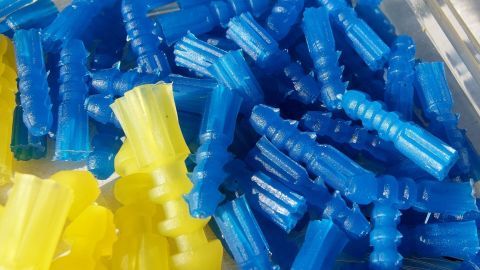 Bunte Dübel aus Kunststoff liegen ordentlich gestapelt, bereit für den Einsatz mit Blitzzement in einem Baukontext.