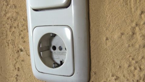 Eine weiße Steckdose an einer Wand, die überprüft wird, um sicherzustellen, dass sie nach dem Streichen funktionsfähig ist.