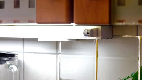 Eine Leuchtstoffröhre schimmert sanft über frischem Gemüse in einer hellen Küche, während sie scheinbar ausgeschaltet ist.