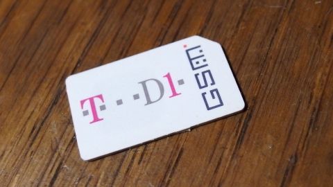 Eine SIM-Karte liegt auf einer Holzoberfläche, um sie einfacher aus einem Handy zu entfernen.