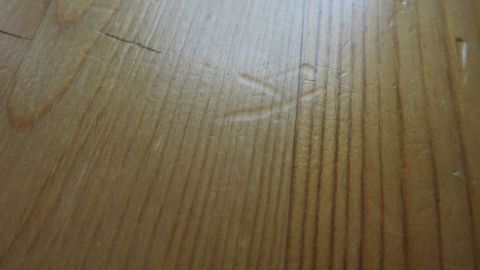 Kleine Dellen im Holz sind sichtbar, die die natürliche Maserung des Holzes stören. Der Boden ist hell und glatt.