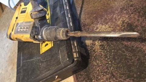 Ein Bohrhammer liegt auf einer Werkbank, bereit, in Beton zu bohren, um eine präzise und kraftvolle Arbeit zu leisten.