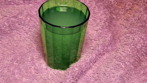 Ein grüner Becher steht auf einem rosa Handtuch, gefüllt mit Molke zur Förderung von super weicher Haut.