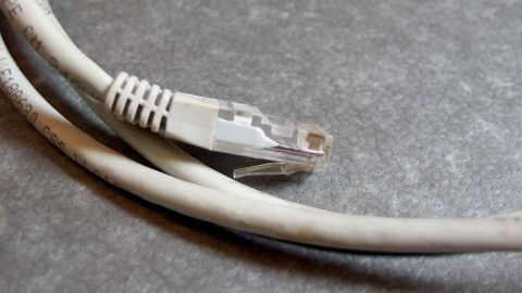 Ein Netzwerk- und ein Verlängerungskabel liegen ordentlich auf einer grauen Oberfläche, bereit für den Einsatz ohne Kabelsalat.