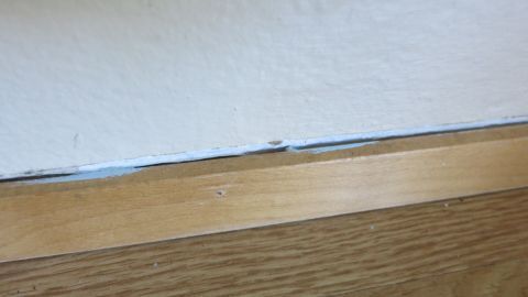 Unerwünschte Spalten zwischen Wand und Sockelleiste lassen sich hervorragend mit Acryl abdichten. Ein unschöner Spalt zwischen Wand und Sockelleiste ist sichtbar, der aus der Nähe fotografiert wurde.