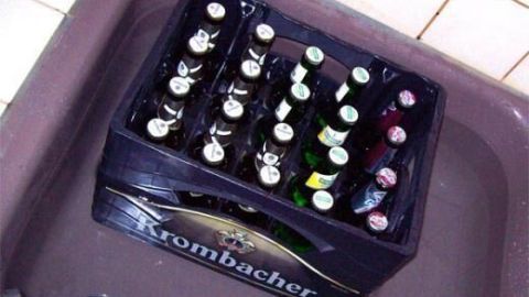 Eine Kiste Bier steht in einem Waschbecken mit Wasser, um sie ohne Kühlschrank kaltzustellen.