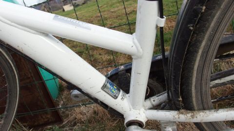 Ein weißes Fahrrad steht auf dem Gras, während die Pflege für den Winter an diesem Fahrrad durchgeführt wird.