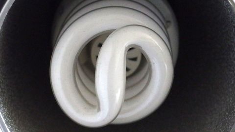 Eine Energiesparlampe flackert im Dunkeln und vermittelt ein flimmerndes Licht, während sie in einer Lampenfassung steckt.
