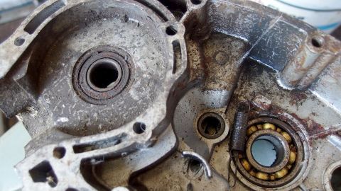Ein verschmutztes Motorenteil mit Ölablagerungen liegt auf einem Arbeitsbereich und wartet darauf, gereinigt zu werden.