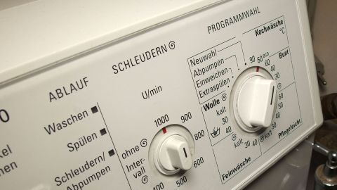 Eine Waschmaschine mit verschiedenen Einstellungen steht im Vordergrund, während ihre Tasten nicht mehr reagieren.