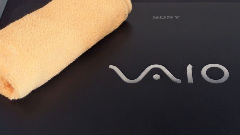 Ein Sony Vaio Notebook liegt auf einer Oberfläche, während ein orangefarbenes Tuch daneben für die Reinigung bereitliegt.