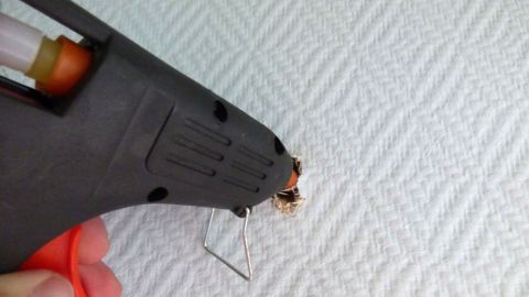 Eine Heißklebepistole wird auf eine strukturierte Oberfläche gerichtet, um ein Bohrloch schnell zu reparieren.