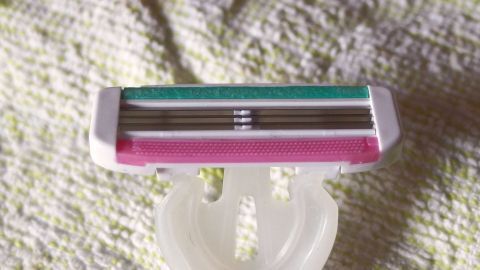 Damit Rasierklingen länger ihre Funktion behalten, sollte man sie zwischen den Klingen regelmäßig reinigen. Ein Rasierer mit scharfen Klingen liegt auf einem hellen Handtuch, bereit für die Anwendung und verspricht längere Nutzung.