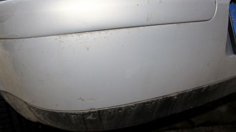 Ein Auto mit hartnäckigem Schmutz am Lack steht im Fokus, sichtbar an der unteren Stoßstange.