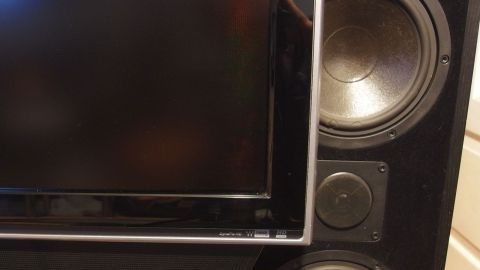 Ein Fernseher steht neben großen Lautsprechern in einem Wohnzimmer, bereit zum Einsatz für Unterhaltungstechnik.