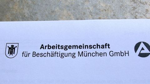 Ein offizielles Dokument zeigt das Logo der Arbeitsgemeinschaft für Beschäftigung München GmbH, zur Unterstützung von Hartz IV.