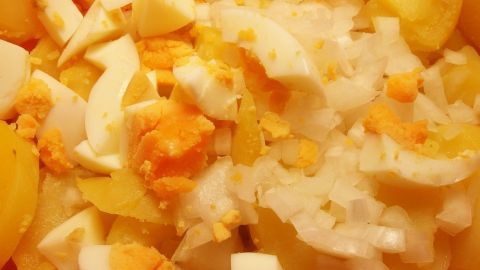 Ein bunter Kartoffelsalat mit gewürfelten Kartoffeln und Eiern, frisch zubereitet in einer Schüssel.