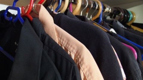 Hängende Kleidungsstücke in einem Kleiderschrank zeigen einen Ausmist-Prozess für den Männerkleiderschrank.