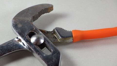 Eine Rohrzange hält sicher an einem glänzenden Chromteil, bereit, es zu befestigen oder zu lösen, ohne Kratzer zu hinterlassen.