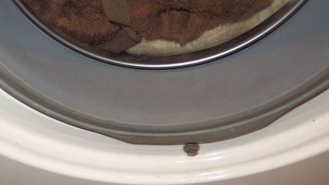 Ein gerissener Waschmaschinengummi ist sichtbar im Türbereich, umgeben von einem Handtuch im Inneren der Maschine.
