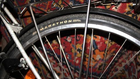 Ein Fahrradreifen liegt auf einem bunten Teppich, während das Werkzeug bereit ist, um den Fahrradmantel zu entfernen.