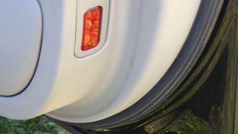 Dichtungsgummi an den Autotüren mit Weichspüler einreiben - so bleiben sie auch im Winter immer elastisch und wasserdicht. Ein Auto mit einer weißen Tür wird mit Weichspüler behandelt, während Gras im Hintergrund sichtbar ist.