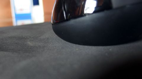 Eine Maus bewegt sich auf einem Moosgummi-Mauspad in einem Büro-Umfeld mit verschwommenem Hintergrund.