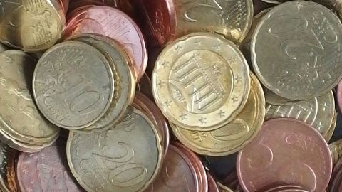 Eine Ansammlung von Münzen liegt verstreut auf einer Oberfläche, während sie für kleine Freuden gespart werden.
