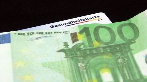 Eine Gesundheitskarte liegt neben einem 100-Euro-Schein, was auf Rückerstattung von der Krankenkasse hinweist.