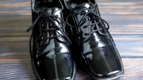 Schwarze Herrenlackschuhe glänzen auf einem Holzuntergrund, bereit für besondere Anlässe.