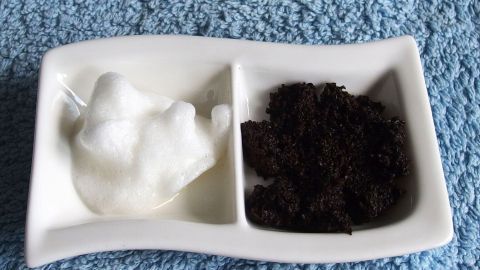 Weißer Joghurt und dunkles Kaffeepulver liegen in einer Schale, bereit zur Anwendung gegen Tränensäcke auf blauer Unterlage.