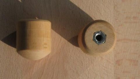 Holzklotz mit Schraubmutter, auf Holzoberfläche positioniert. Eine Perspektive zeigt die Mutter eingepresst im Holz.