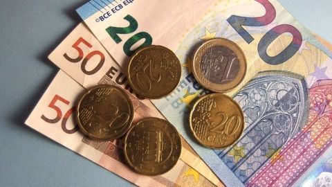 Fünf Münzen liegen auf einem Stapel von Euro-Scheinen, was auf Möglichkeiten zum Extra Geld machen hinweist.