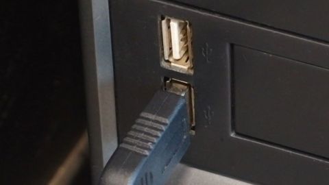 Ein USB-Ladekabel ist in einen Computeranschluss eingesteckt, während der Nutzer versucht, Strom zu sparen.
