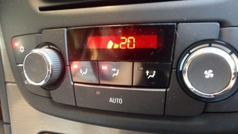 Das Bedienfeld der Klimaanlage zeigt eine Temperatur von -20 Grad, während das Auto in einem modernen Innenraum steht.