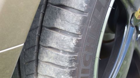 Abgenutzter Autoreifen zeigt verschlissene Profilrillen und ist Teil eines gepflegten Fahrzeugs in einer städtischen Umgebung.