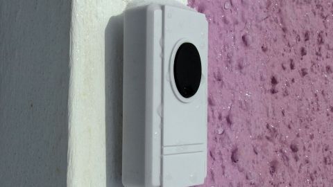Eine weiße Halterung wird an einer lila Wand befestigt, ganz ohne zu bohren, um eine einfache Anbringung zu ermöglichen.