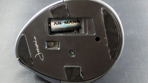 Eine schwarze Funkmaus liegt auf einer Oberfläche, während sich eine Batterie im Inneren befindet, um unnötigen Batterieverbrauch zu vermeiden.