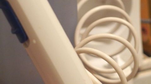 Ein brauner Mundduschenschlauch ist sichtbar und hängt in einer Spirale, bereit zum Einsatz in einem Badezimmer.