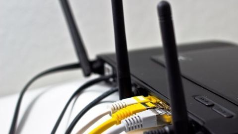 Router mit sichtbaren Antennen und Kabeln, zeigt WLAN-Verbindung in einem häuslichen Umfeld.