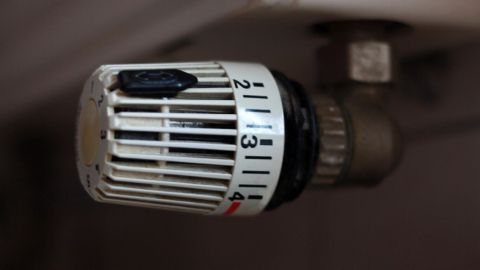 Ein Heizkörperthermostat, das auf eine Temperatur eingestellt wird, befindet sich am Heizkörper in einem Wohnraum.