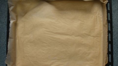 Ein Backblech ist mit Backpapier ausgelegt, bereit zum Befüllen mit Mürbeteigboden für ein Rezept.