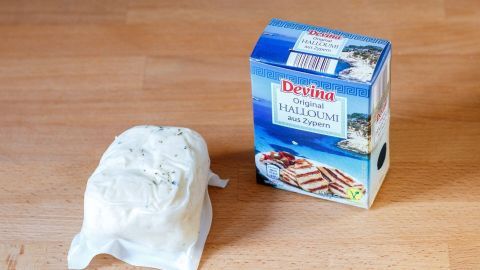 Der beste Grillkäse für Vegetarier ist Halloumi. Er schmeckt hervorragend, beim Grillen wird er schön braun und knusprig. Halloumi liegt verpackt neben einer geöffneten Box auf einem Holzuntergrund, bereit zum Grillen für Vegetarier.