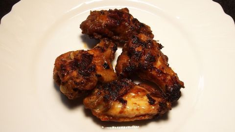 Krosse Chicken Wings liegen appetitlich auf einem weißen Teller und sind bereit zum Genießen.