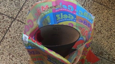 Ein bunter Müllsack steht auf einem gefliesten Boden und hält einen großen Behälter, der in einem Gartenstiefel verwendet wird.