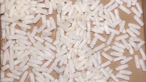 Weiße Verpackungsfüllung liegt verstreut auf einem Karton, ideal um Blumenerde gut durchlüften zu können und sie zu schützen.