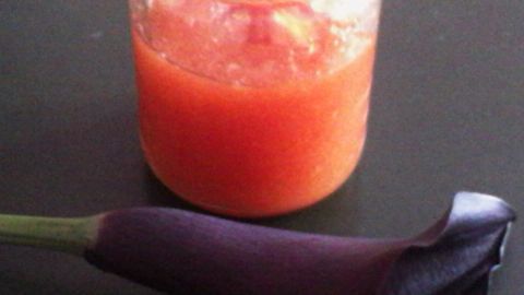 Ein Glas Marmelade steht auf einem Tisch, während eine schwarze Calla-Lilie daneben liegt.